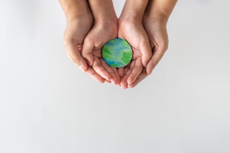 Adult and child hands gently holding a small Earth model, symbolizing global unity, care, and the importance of supporting mental health for all.