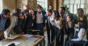 A diverse team of colleagues standing close together, smiling and supporting one another in an office setting—symbolizing strong team connection and the cultural value of employee retention in startups.