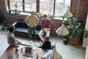 Small team of diverse startup employees engaged in a casual, collaborative meeting in a modern loft office—symbolizing early-stage company culture and open communication before scaling.