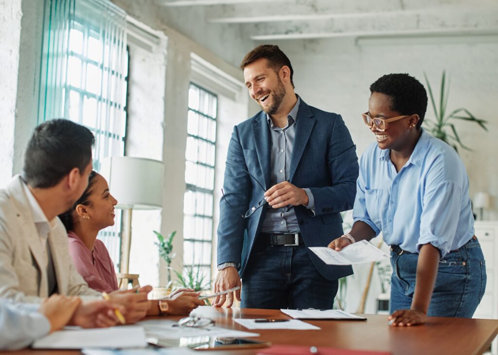 A group of coworkers smiling and collaborating during a team meeting, reflecting a positive, high-trust workplace culture that supports strong startup valuation.