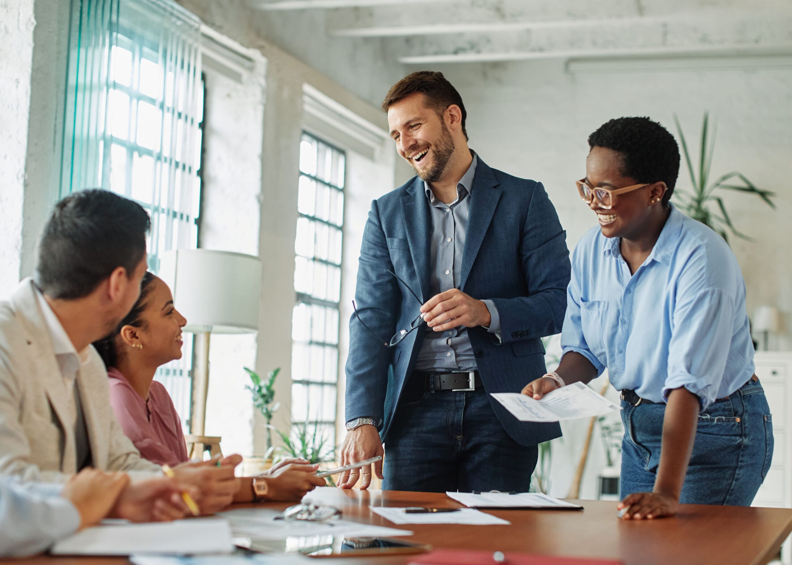 A group of coworkers smiling and collaborating during a team meeting, reflecting a positive, high-trust workplace culture that supports strong startup valuation.