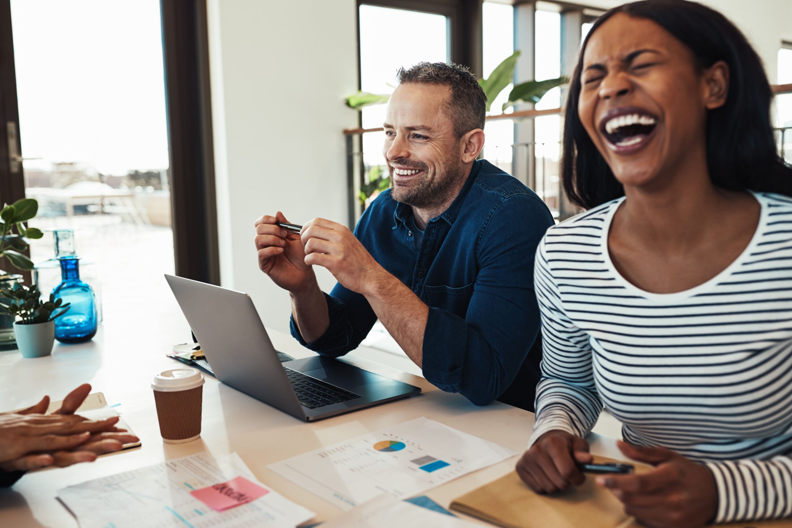 A group of coworkers smiling and laughing together during a meeting, reflecting strong team happiness, connection, and a positive startup culture.