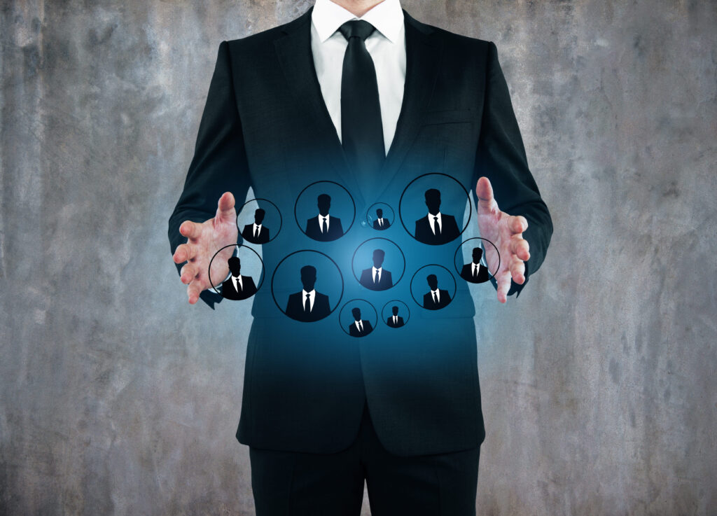 A business professional in a suit standing with hands open around a glowing hologram of team member icons, symbolizing a scalable people operations system and organized workforce management.
