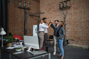 A group of excited team members standing together in an office, celebrating with a high-five, symbolizing alignment, teamwork, and a ready-to-scale startup culture.