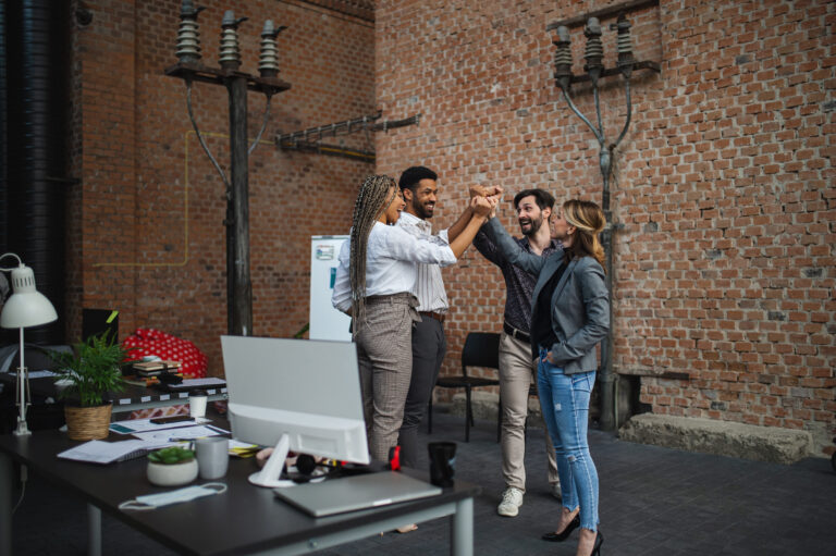 A group of excited team members standing together in an office, celebrating with a high-five, symbolizing alignment, teamwork, and a ready-to-scale startup culture.