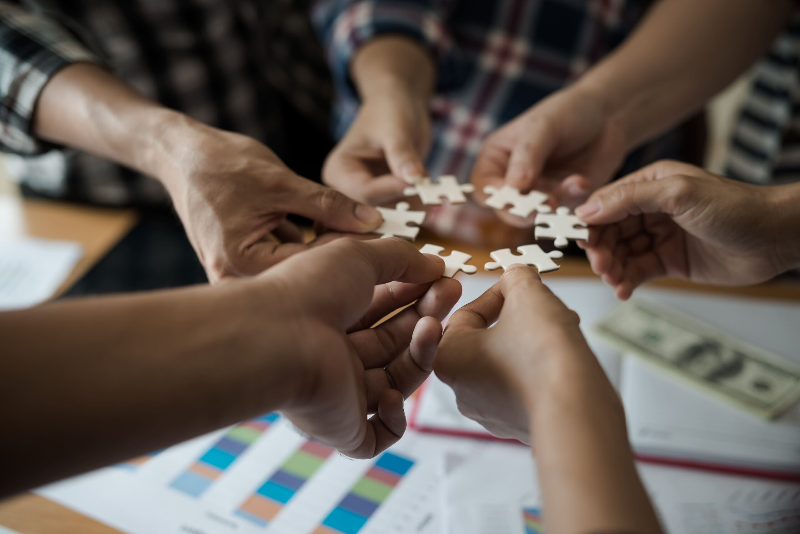 Hands of diverse employees assembling puzzle pieces, representing personalized employee benefits coming together to meet individual needs