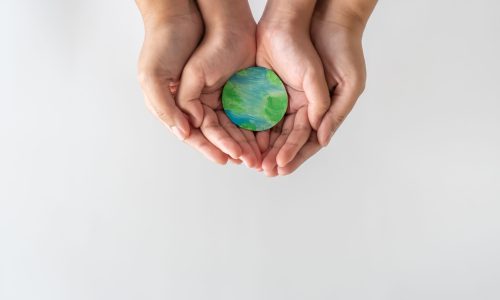Adult and child hands holding the earth on hand. Concept of saving the world from global warming.